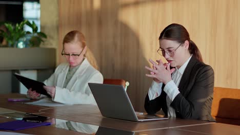 tired businesswoman takes a short break and inhales and exhales during a hard day at work at her desk in a modern office. a brunette girl in a business suit takes a short break and warms up during her work in the office