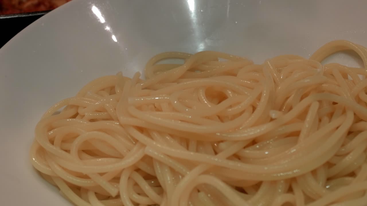 Primo piano di spaghetti con salsa di melanzane in una ciotola bianca.