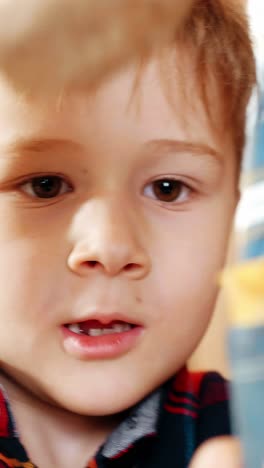 young boy with light brown hair is holding a colorful toy while gazing curiously at the camera, showcasing childhood innocence and playful spirit