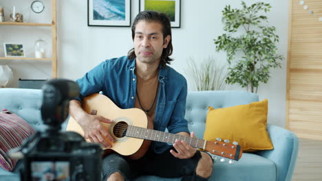 hombre tocando la guitarra acústica en casa