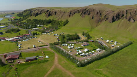 Vista-Aérea-De-La-Verde-Campiña-De-Islandia-Con-Camping-Para-Turistas.-Vista-De-Drones-Del-Pequeño-Pueblo-En-El-Prado-Verde-De-Las-Tierras-Altas-Islandesas