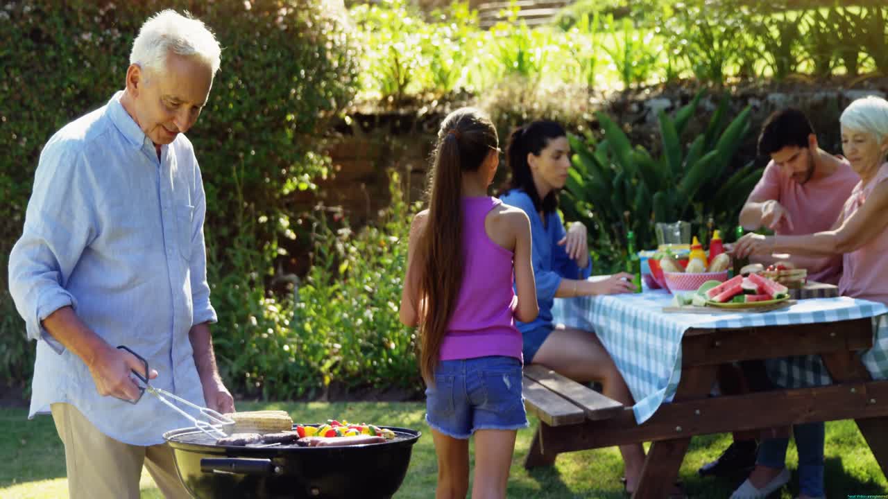 할아버지 와 손녀 가 가족 이 식사 하는 동안 바베큐 를 준비 하고 있다 4k