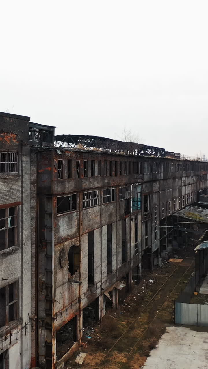 Aerial view of an old factory ruin and broken windows. Old industrial building for demolition. Vertical video