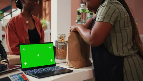 merchant selling eco goods next to greenscreen laptop