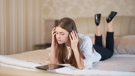 hermosa mujer acostada en la cama con auriculares y con una tableta