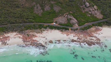 drone flying above coastal road with camper van parked on the side of the road