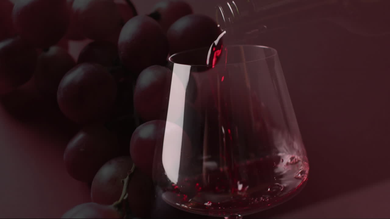compuesto de vino tinto que se vierte en un vaso sobre uvas sobre un fondo rojo