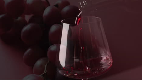 composite of red wine being poured into glass over grapes on red background