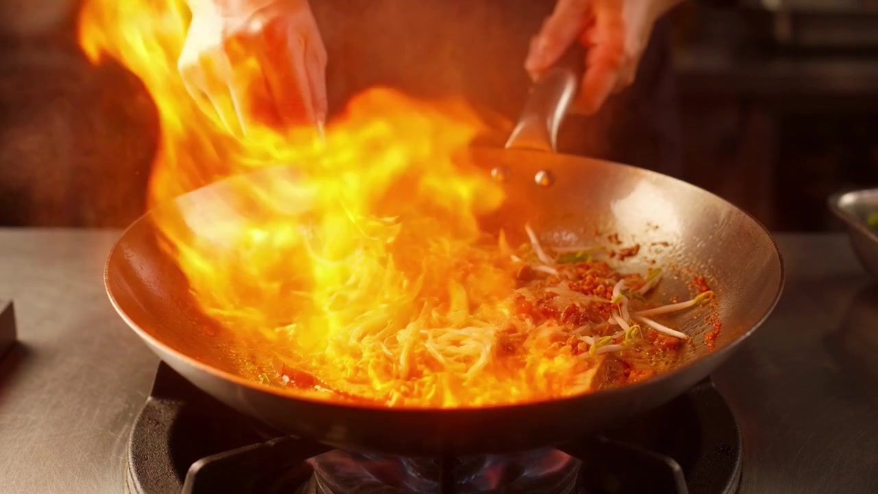 Chef che salta noodles Pad Thai in un wok con fiamme