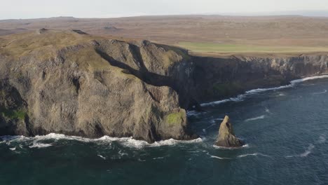 aerial approaching shot of ketubjörg cliffs with waves of ocean during sunny day on iceland