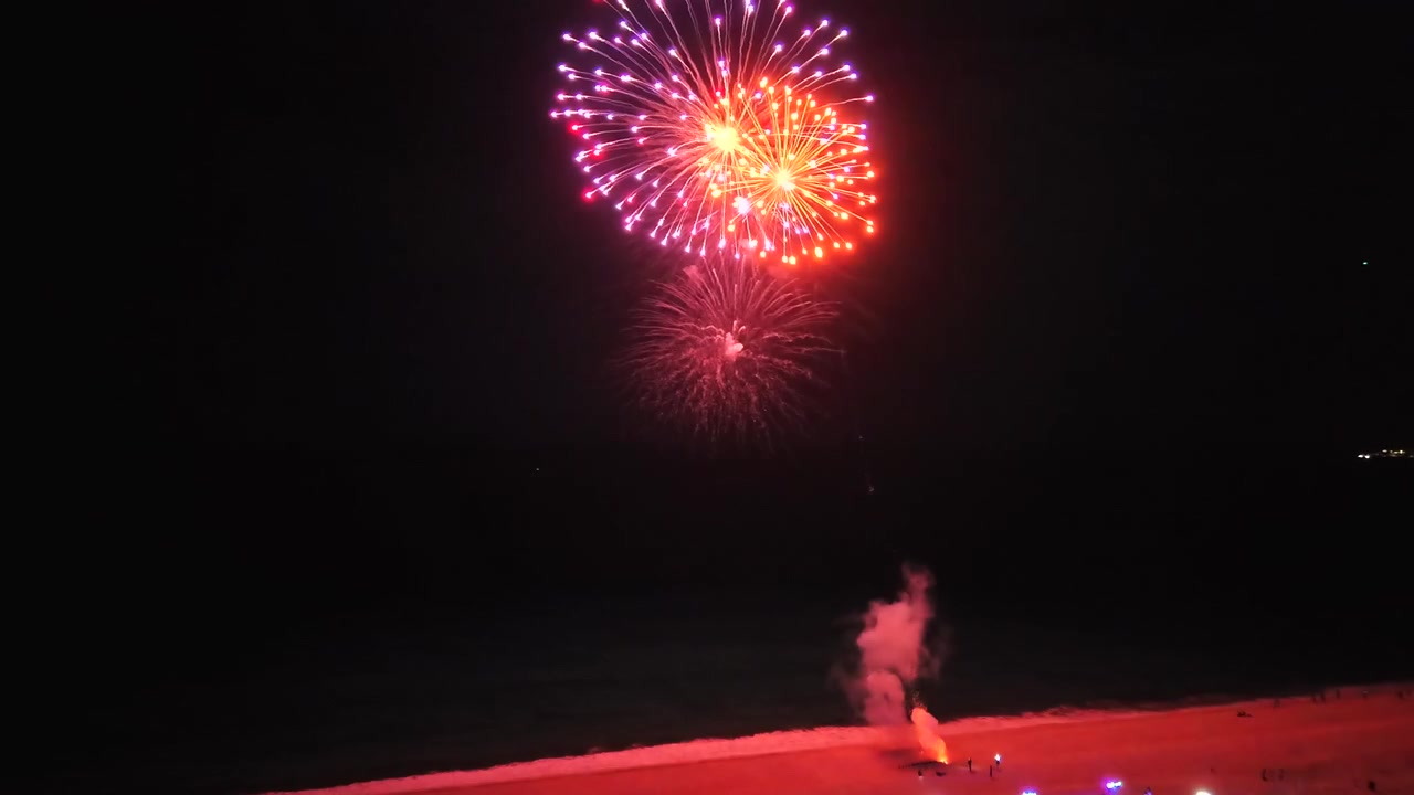 4K drone over the ocean facing San José del Cabo, capturing multiple fireworks displays along the coastline at night.