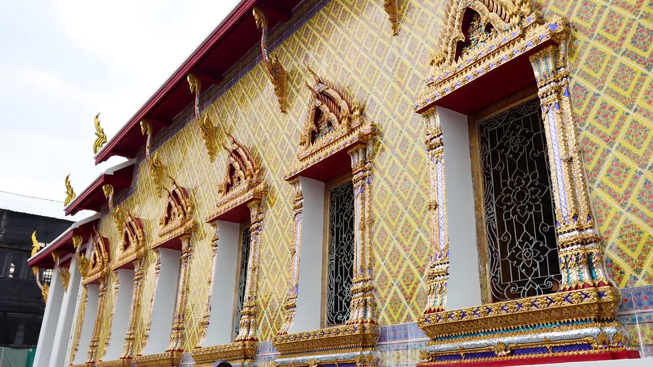 Una vista dettagliata dell'intricata facciata del tempio Wat Pho, che mostra l'architettura tradizionale thailandese con colori vivaci e disegni ornamentali.