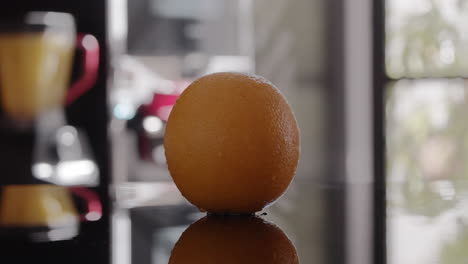 un primer plano de una naranja húmeda girando en una superficie brillante