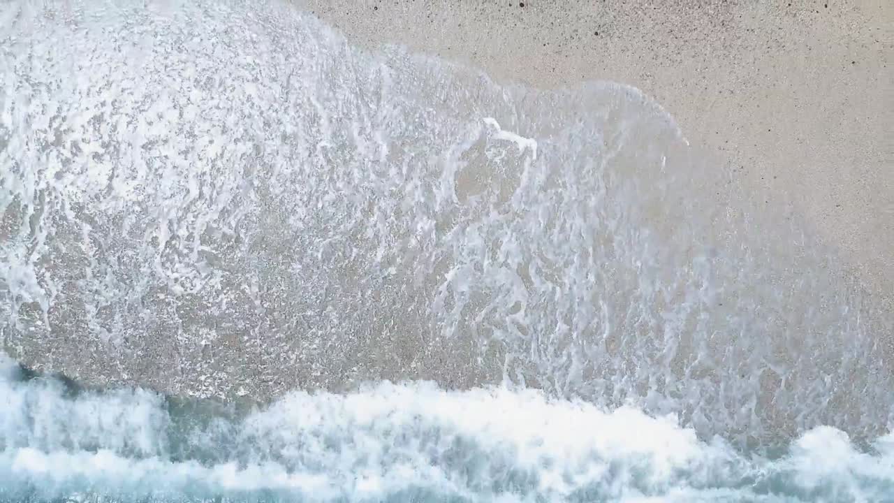 하얀 자갈 해변에 부서지는 바다의 파도 위로 드론이 오름차순