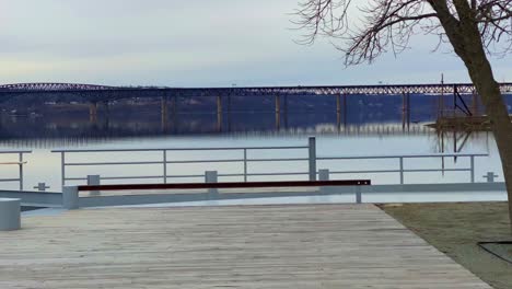 a large wooden dock patio overlooking the hudson river and toward the city of newburgh, new york, as seen from beacon, new york