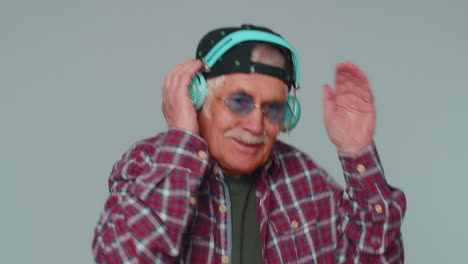 hombre alegre y atractivo escuchando música a través de auriculares y bailando discoteca burlándose de divertirse
