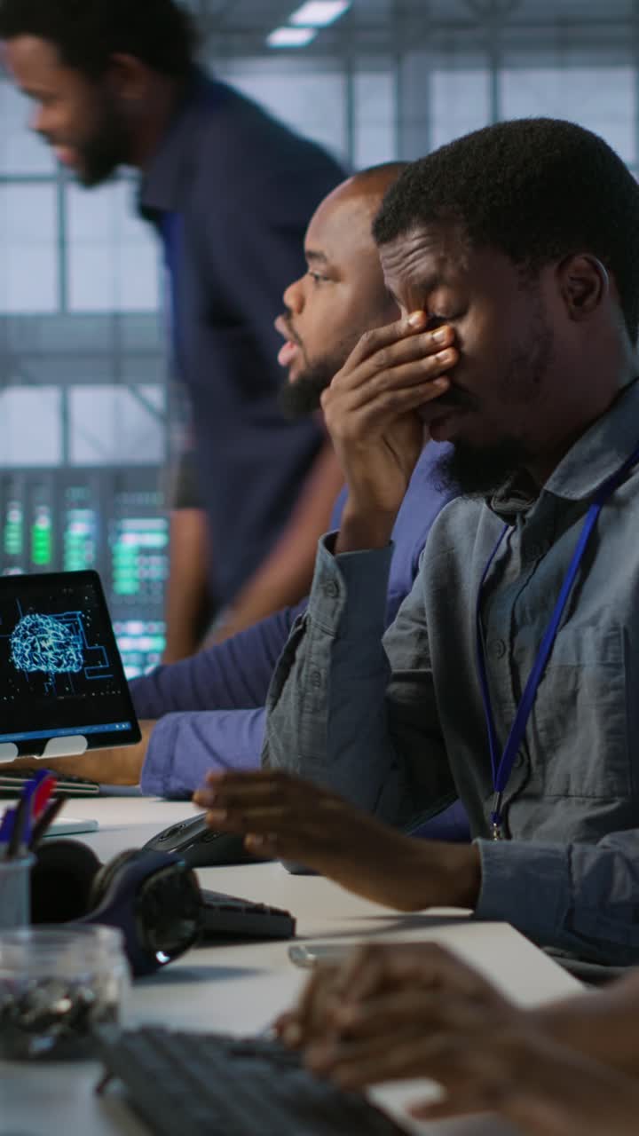 Vertical video Tired data center engineer yawning, suffering from lack of sleep