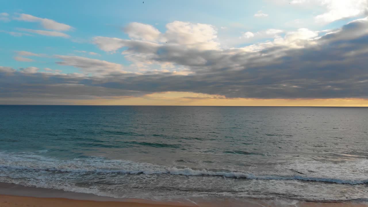 Tramonto sull'orizzonte dell'oceano e piccole onde che si infrangono sulla riva