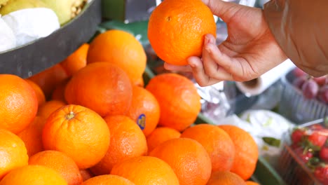 persona comprando naranjas en una tienda de comestibles