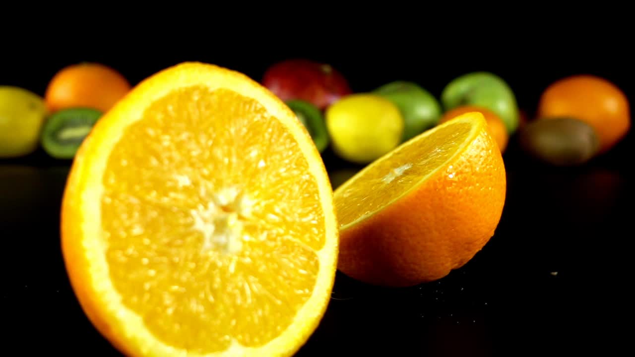 Caduta di un'arancia sullo sfondo della frutta. Rallentatore