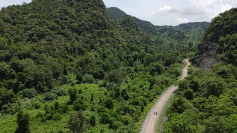 drone moves upward from road to reveal vast jungle and mountain