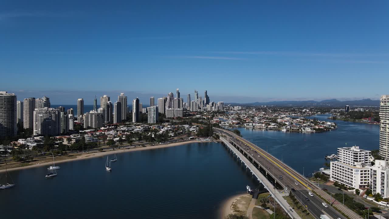 vista alta de un puente importante y una carretera que desemboca en una ciudad llena de edificios de gran altura y rodeada de agua.