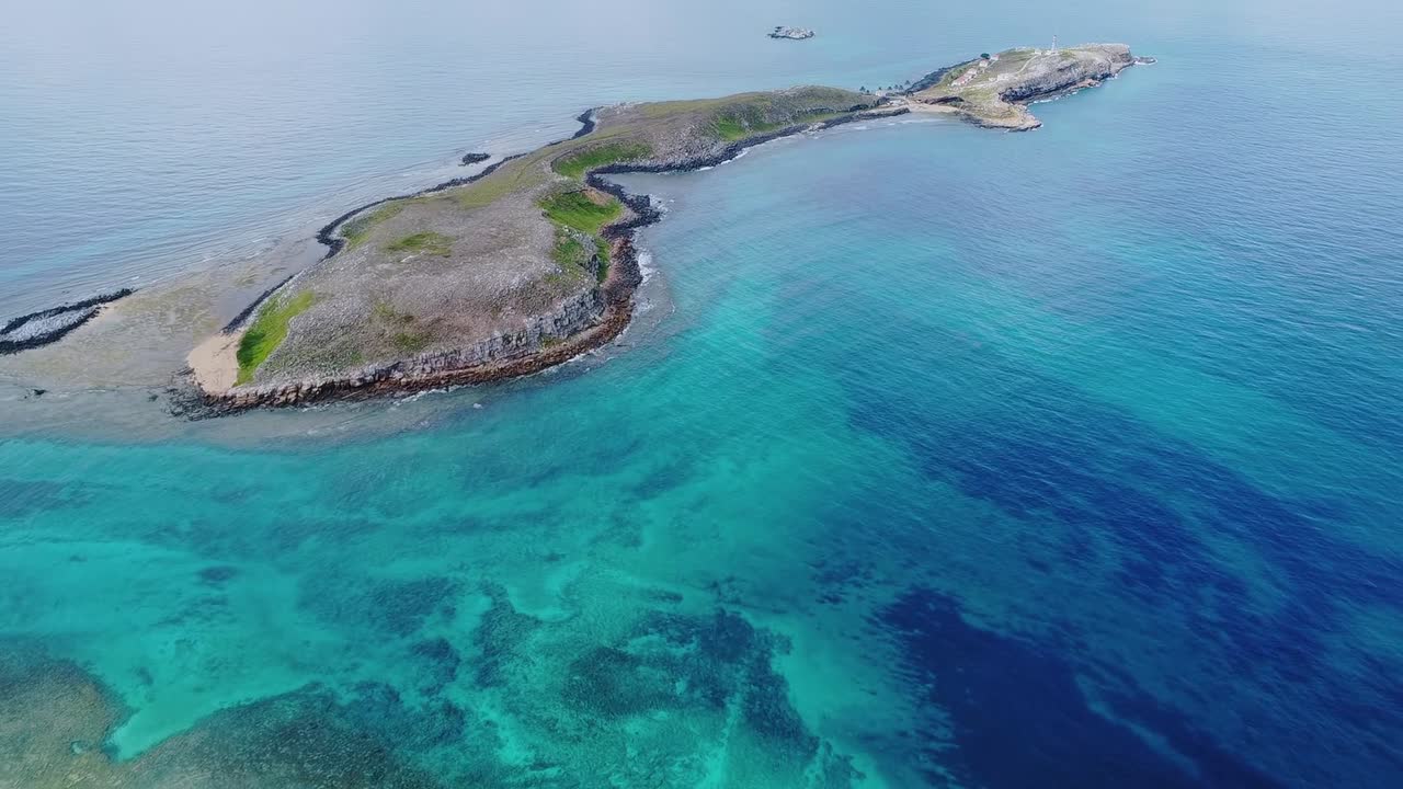Arcipelago di Abrolhos con una piccola isola circondata da acque cristalline dell'Oceano Atlantico e diverse formazioni coralline sottomarine, che rappresentano un ricco ecosistema marino, sorvolo in avanti con drone.