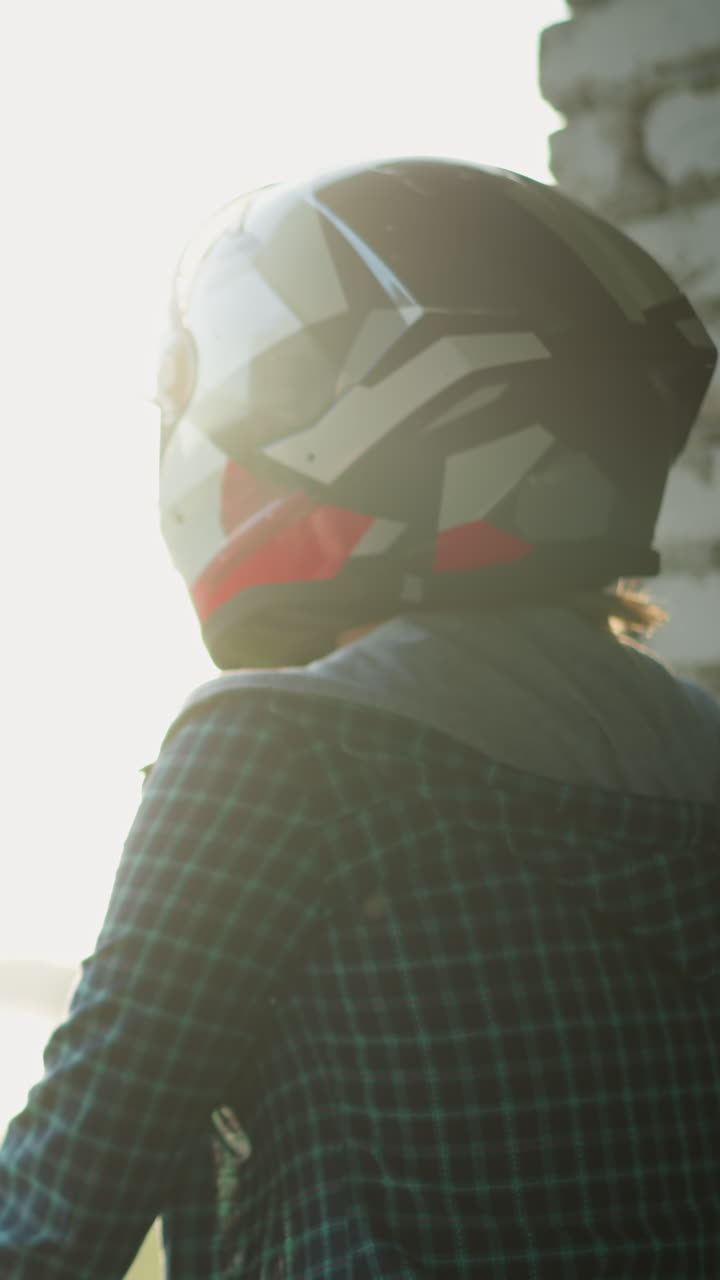 vista trasera de dos mujeres con cascos de pie cerca de una ventana, mirando hacia afuera hacia una estructura borrosa en el fondo