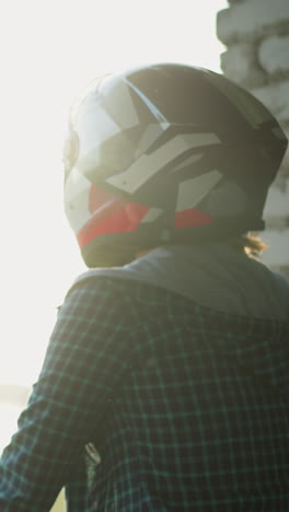back view of two women in helmets standing close to a window, looking outward toward a blurred structure in the background