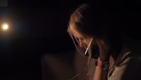 woman in dark room talking on charging mobile