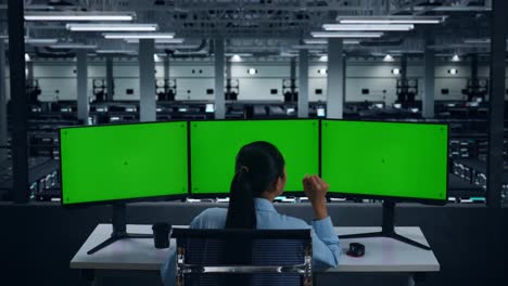 vista trasera de una mujer asiática cansada bostezando mientras trabajaba con un simulacro de varios monitores de computadora en un centro de datos