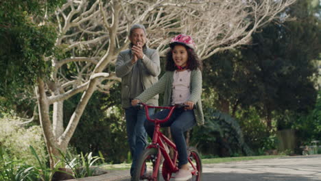 grandfather teaching child to cycle on her first