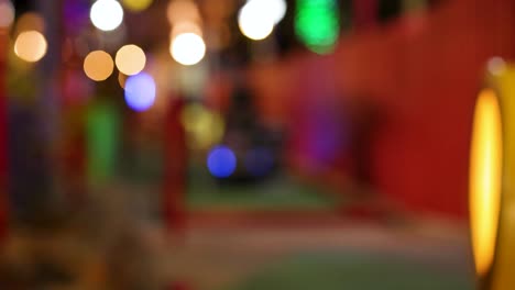 blurred neon-lit miniature golf course with vibrant colors and dynamic lighting, creating a playful and energetic atmosphere