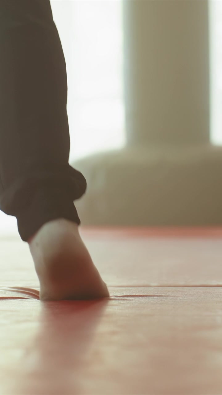 Close up of feet and legs performing slow steps. Feet move gradually across light colored red pinkish red surfaces. Silhouettes create contrast against bright backgrounds