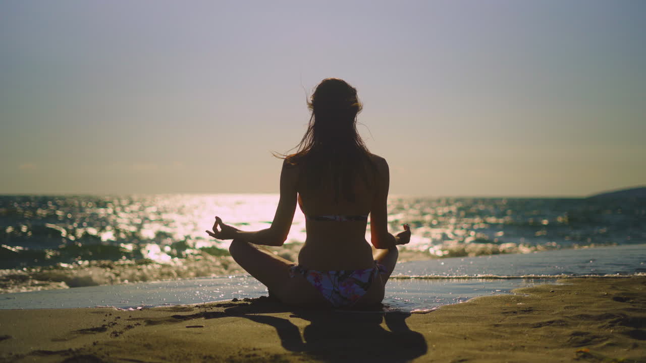 mujer meditando en la playa al atardecer