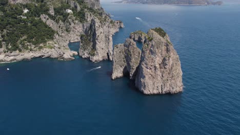 sheer cliff faces of dramatic faraglioni sea stacks, capri coastline aerial