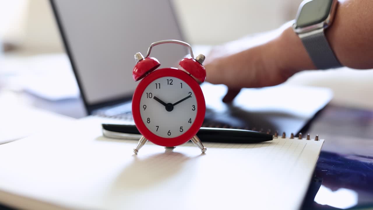 Time management at work with alarm clock and laptop