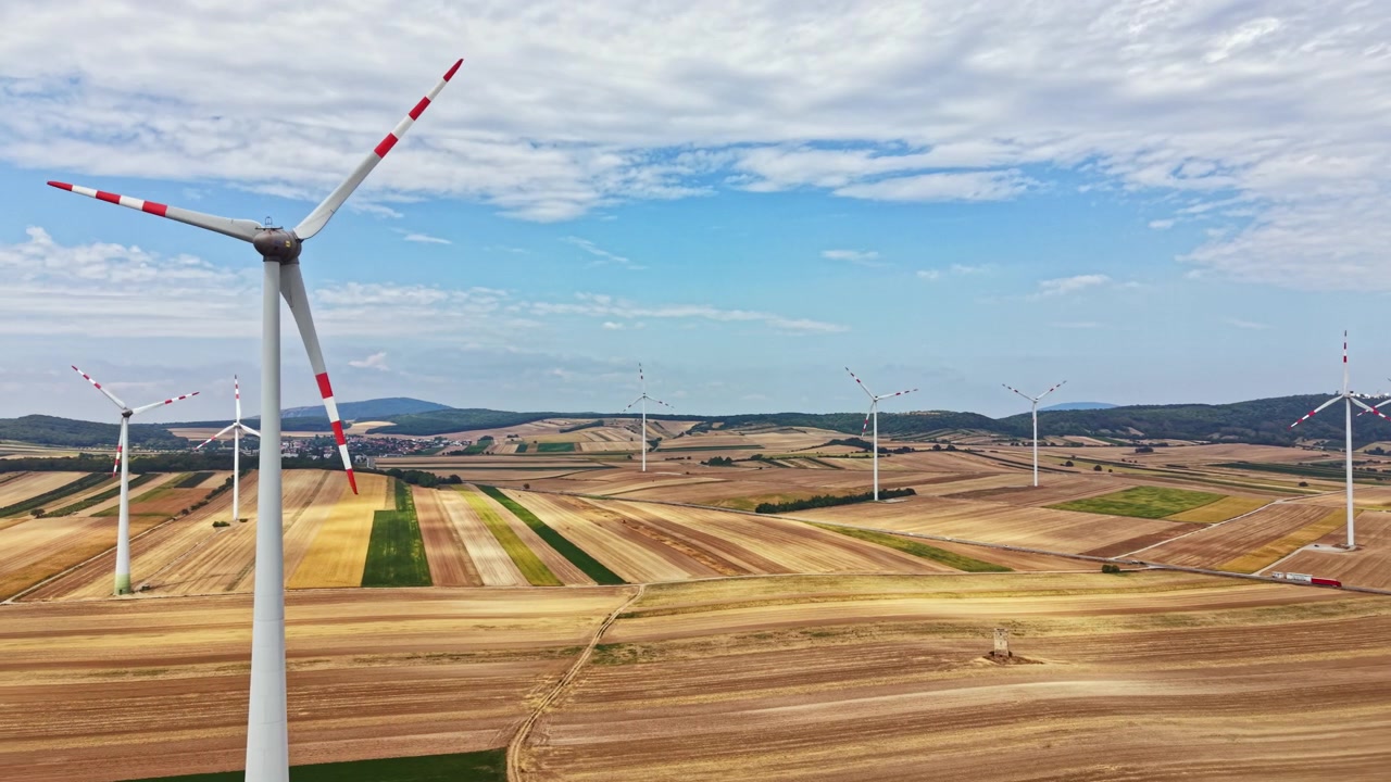 Wind turbines in fields under a clear sky during the day in a rural area near the mountains