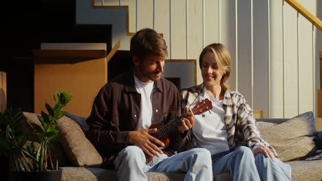 pareja tocando el ukulele en el sofá durante el movimiento