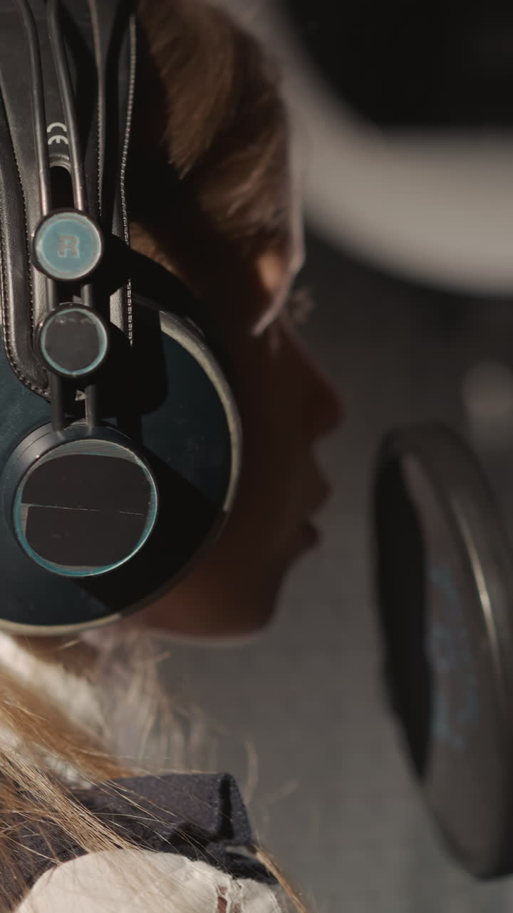 joven cantante rubia actúa en el micrófono. era emergente de la música escénica entre la generación más joven. chica con auriculares en el estudio de grabación de audio