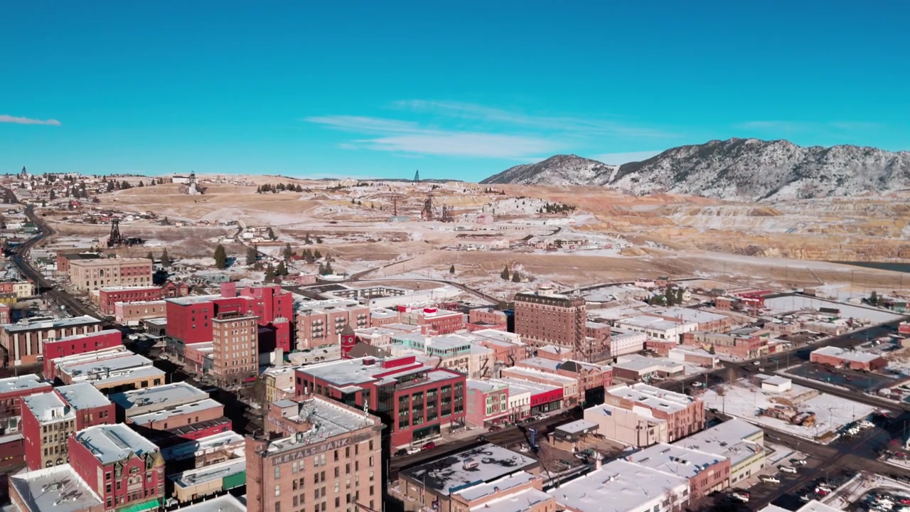 Droneutsikt over sentrum av Butte, Montana, som viser historisk rød mursteinsarkitektur, gamle forretningsbygg og omkringliggende gruveterreng under en klar vinterhimmel