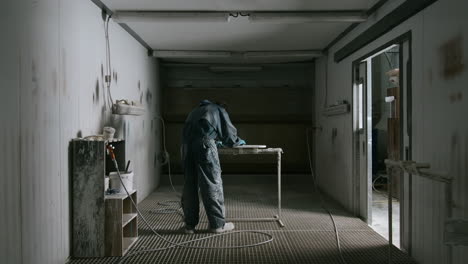 worker in an industrial spray painting facility