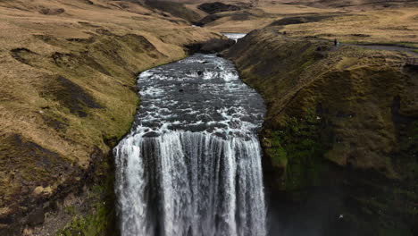 Vista-Aérea-Hacia-Atrás-Sobre-La-Cascada-De-Skogafoss,-Nublado,-Día-De-Otoño-En-Islandia