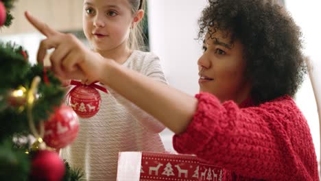 handheld view of charming girl and mommy decorating christmas tree