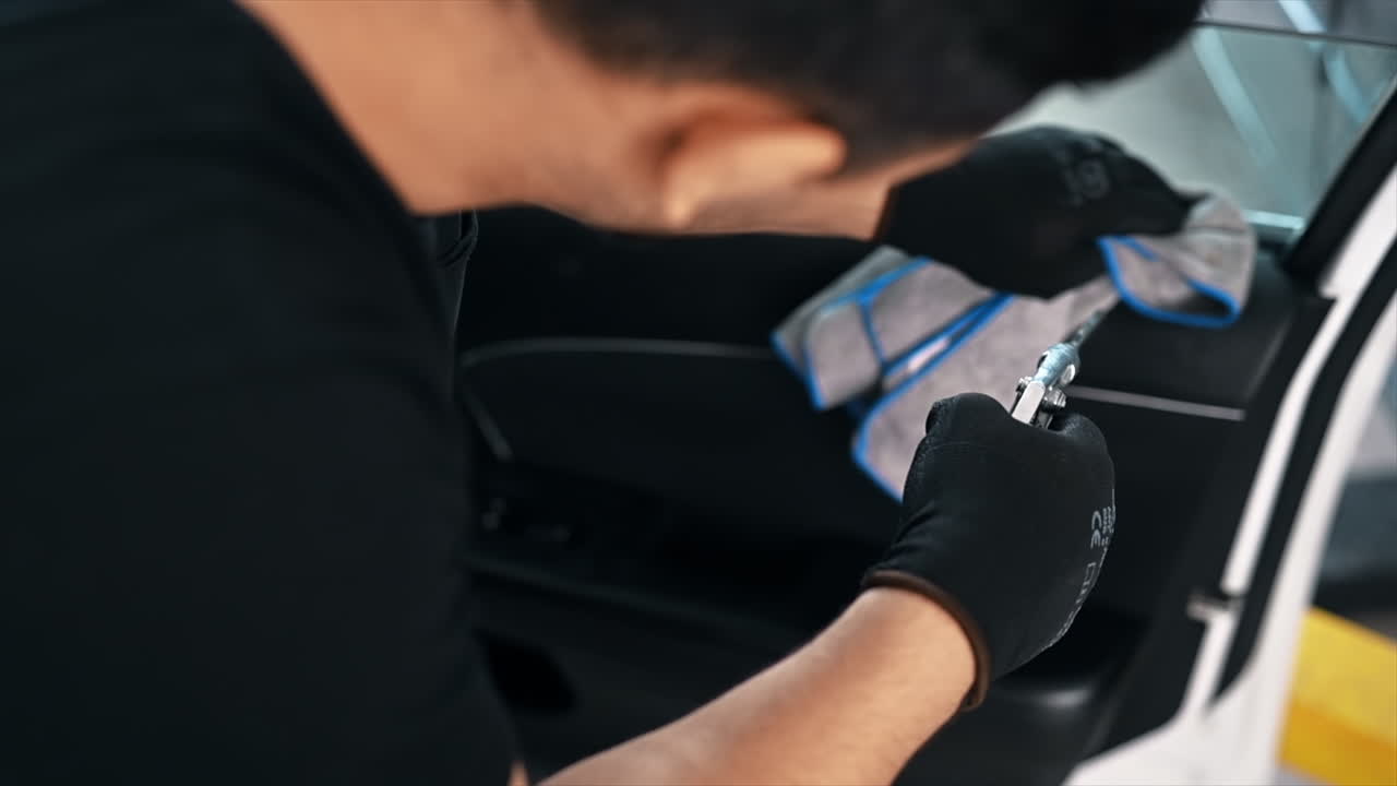 Working cleaner at car wash. Cleaning the door using a rag and compressed air. Slow motion
