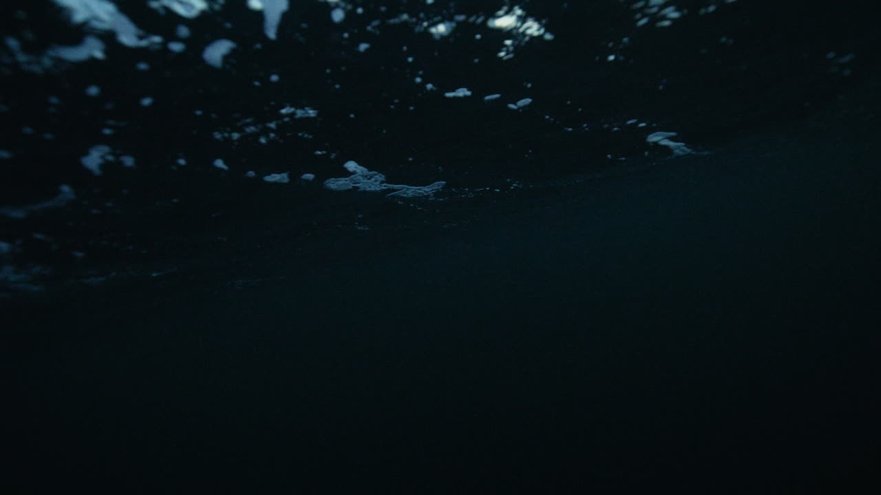 Deep underwater Arctic Ocean with faint light patterns shimmering across dark water