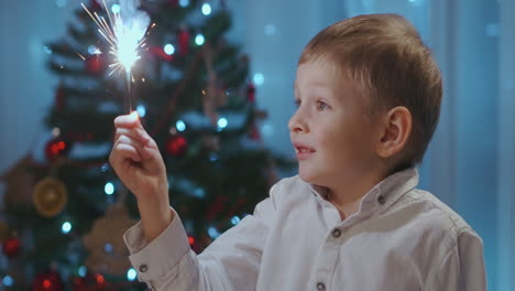 un niño sostiene y mira con alegría a una chispa sentado en la cena en la víspera de navidad. celebrar el año nuevo con chispas. niño 3-5 sostiene un fuego chispa. imágenes de alta calidad 4k