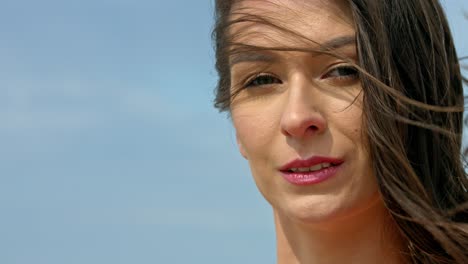 A-young-beautiful-woman-quietly-gazing-into-the-camera-while-her-hair-drifts-over-her-face-in-the-direction-of-wind