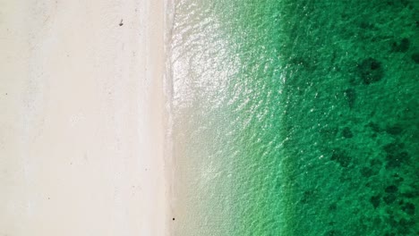 Toma-Aérea-De-Arriba-Hacia-Abajo-De-Una-Playa-Con-Agua-Clara