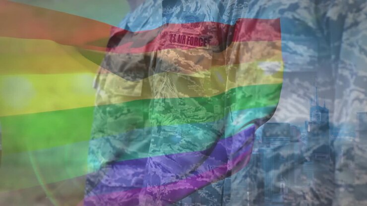 Camera panning revealing three USAF airmen standing under waving rainbow flag showing support